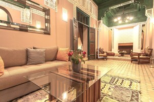 Una sala de estar con sofá, una mesa de centro de vidrio y un jarrón decorativo con flores.
