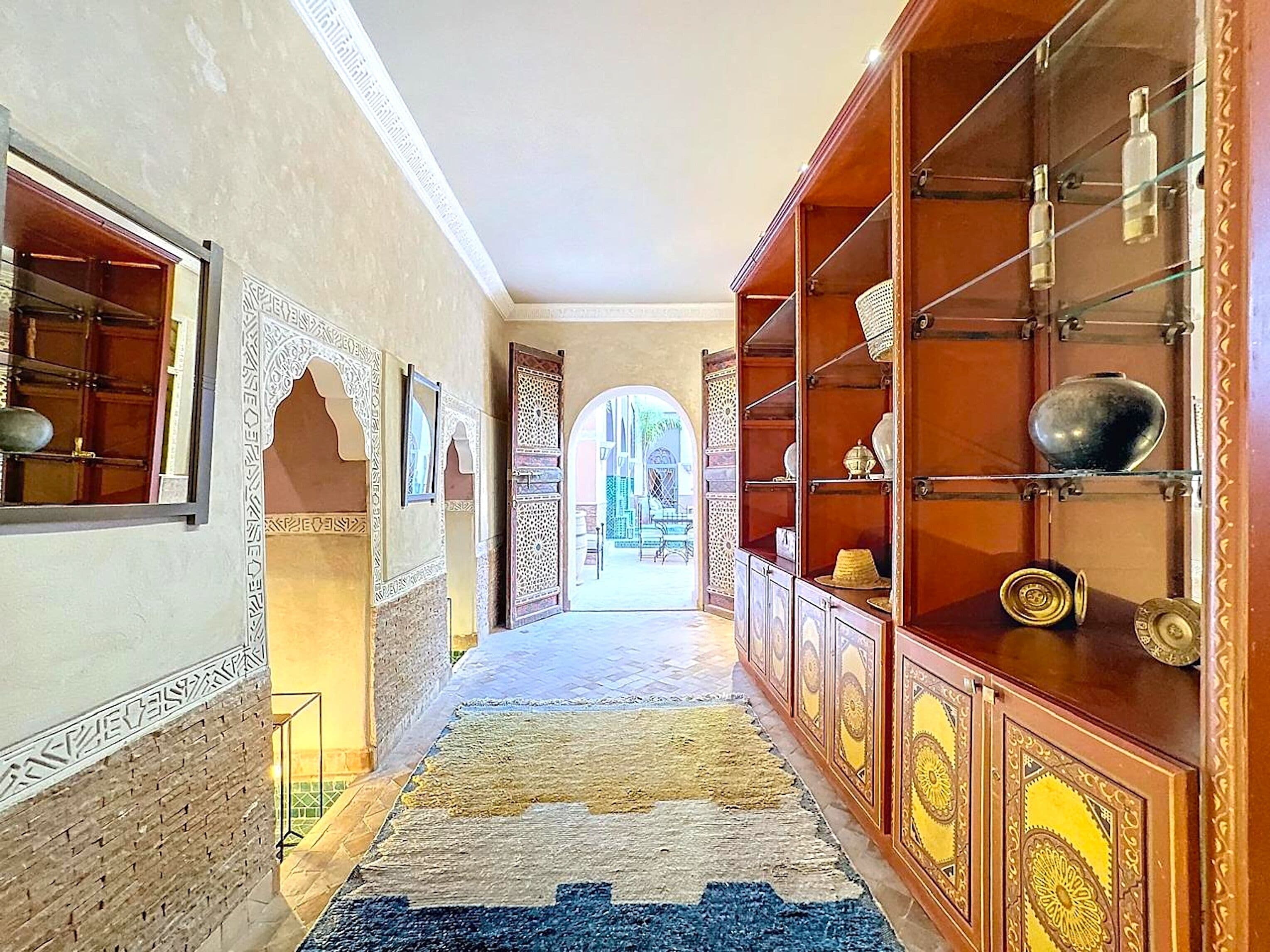 A corridor with ornate wooden cabinets and a patterned rug.