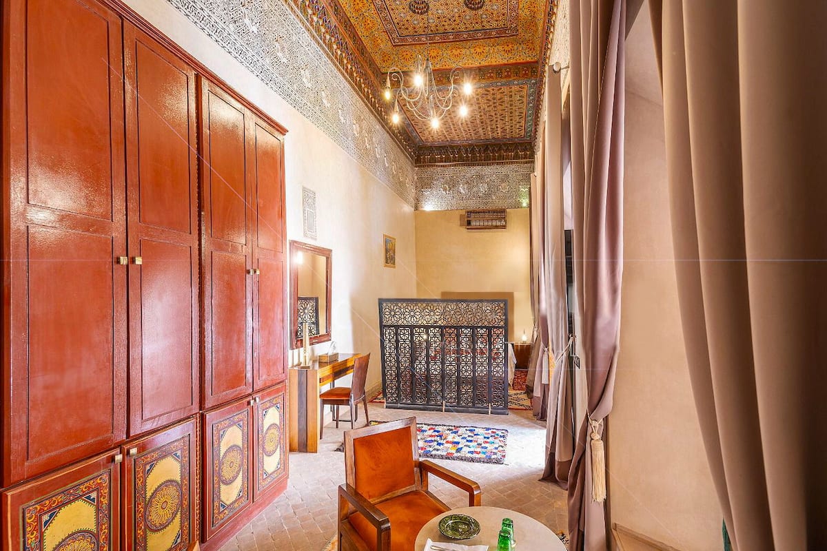 A traditional room with a wooden cabinet, a dining table with chairs, and a decorative ceiling.