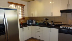 A kitchen with white cabinets, a stainless steel refrigerator, a microwave, a stove, and a dishwasher. - Paradera Paradise (Paradera)