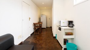 Uma cozinha compacta equipada com geladeira, micro-ondas e cafeteira.