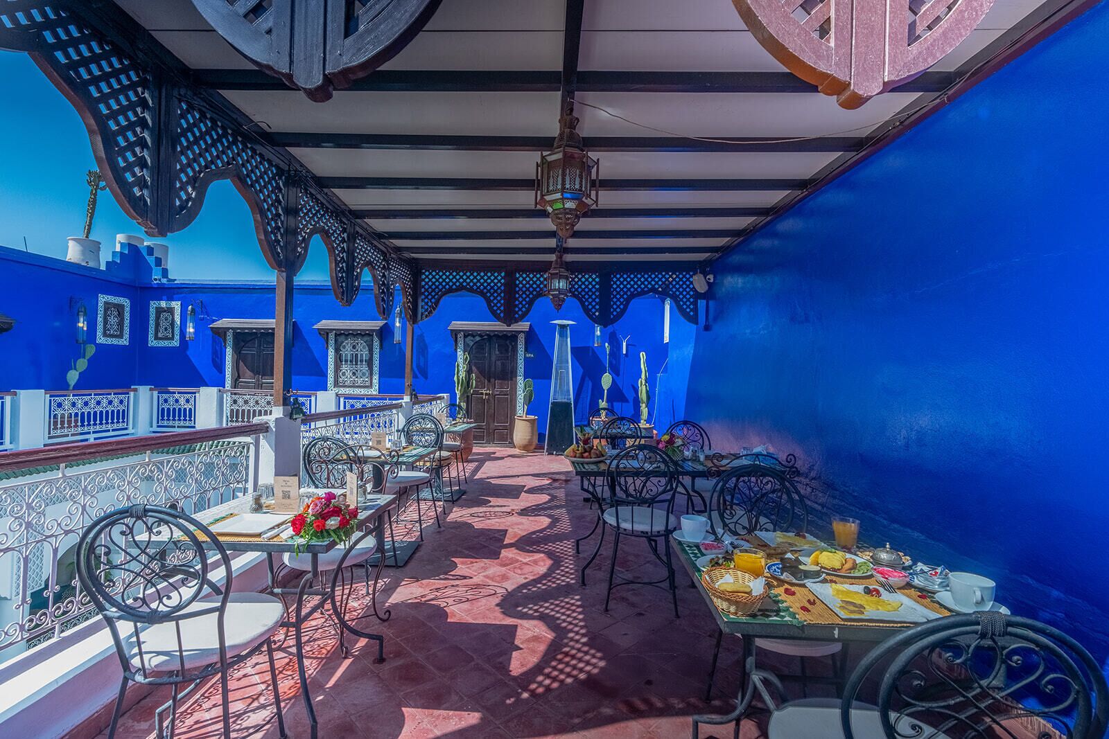 Une terrasse aux murs bleus, dotée de sièges extérieurs et offrant une vue sur la mer.
