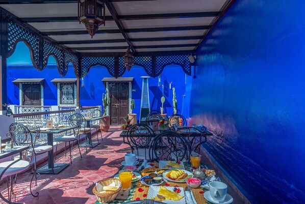 Una terraza con mesas al aire libre, una mesa de desayuno y vista al mar.