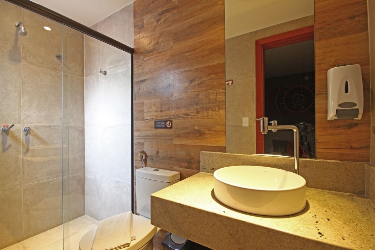 Une salle de bain moderne avec une douche à parois de verre, un lavabo doté d’un plan de toilette en bois et un miroir avec un distributeur de savon.