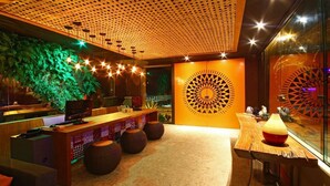 A modern interior with a wooden reception desk, a large decorative wall, and a seating area with round stools. - Bravo Pousada Design (Cabo Frio)