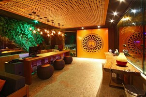 Un interior moderno con un mostrador de recepción de madera, un amplio panel decorativo y una zona de estar con taburetes redondos.