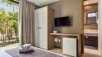 A hotel room with a bed, a TV, a mini-fridge, a bathroom with a sink, and a view of palm trees.