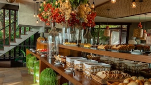 A buffet area with a variety of food items, hanging lights, and potted plants. - Bravo Pousada Design (Cabo Frio)