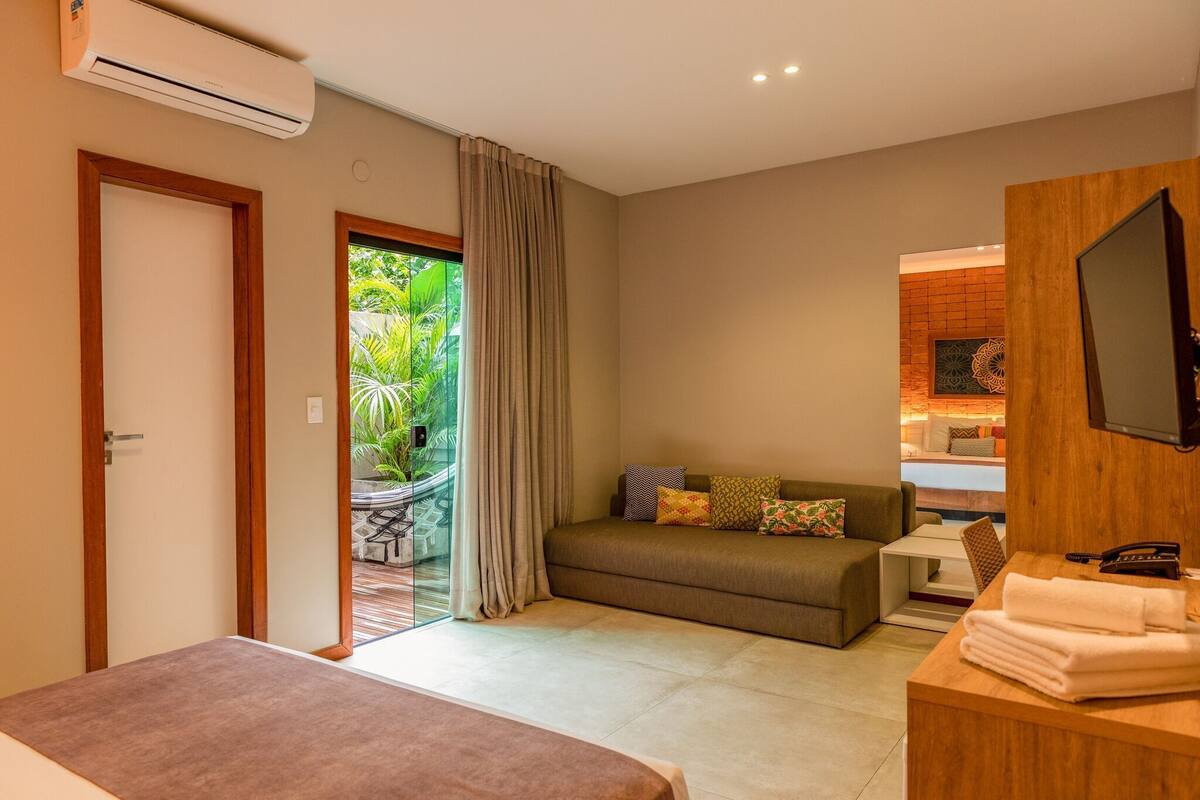 Une chambre d’hôtel avec un lit, un canapé, une télévision et une salle de bain.