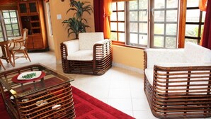 Una sala de estar con muebles de mimbre, una mesa de centro de vidrio y una alfombra roja.