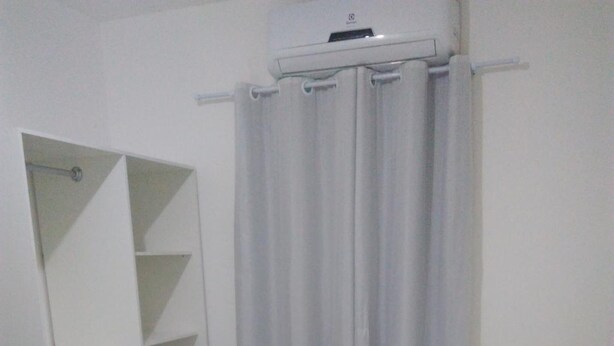 A bedroom with a bed, a wardrobe, and a shower curtain. - Pousada Beira Mar (Recife)