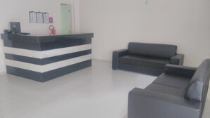 A reception area with a counter, a sofa, and a door. - Pousada Beira Mar (Recife)