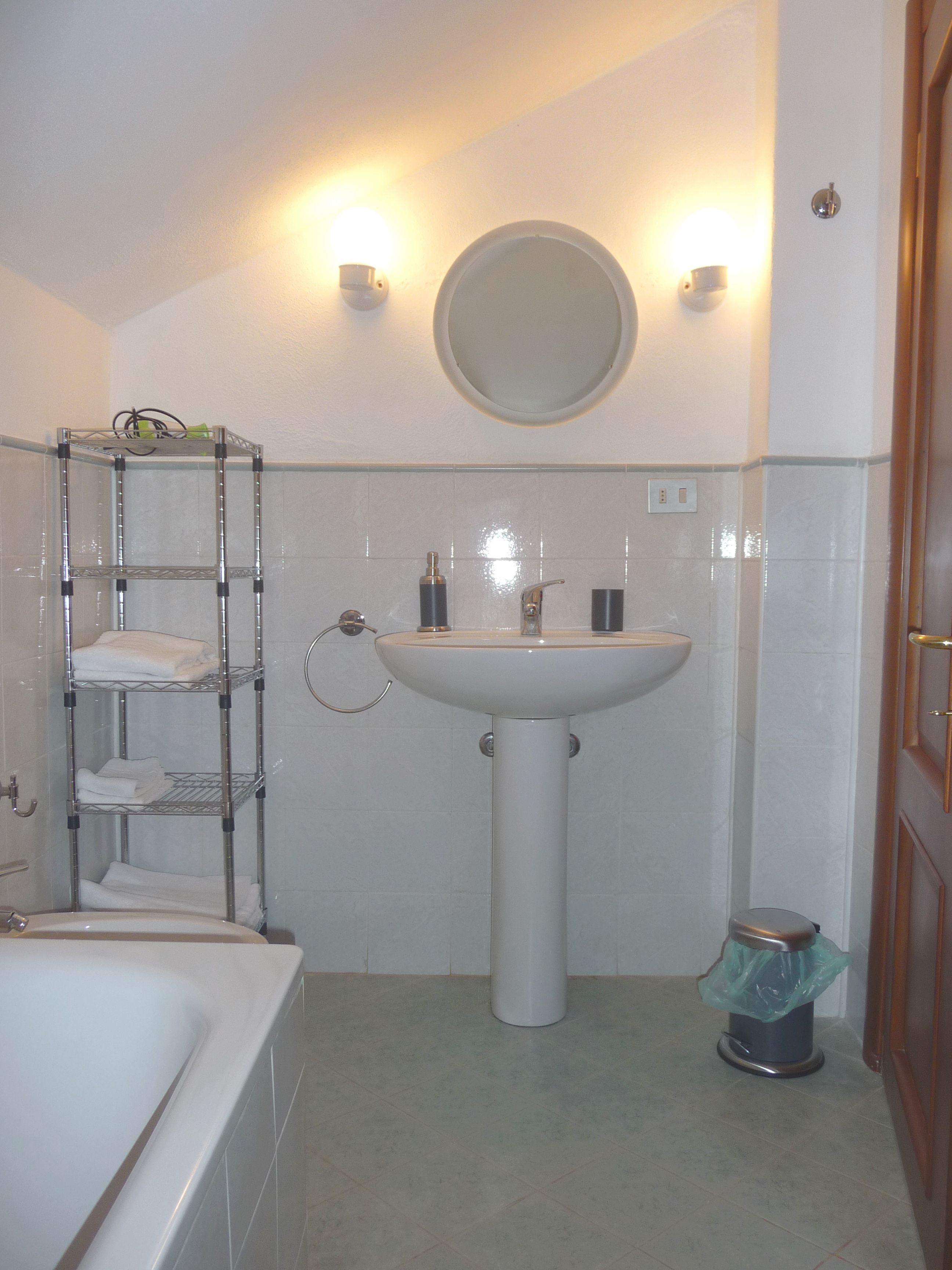 Un baño con lavamanos blanco, un espejo, toallero y un inodoro.