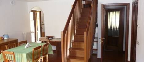 Un comedor con una escalera de madera que sube a un piso superior.