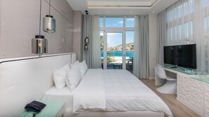 A hotel room with a bed, a desk, a TV, and a view of the sea. - Demi Hotel (Sarandë)