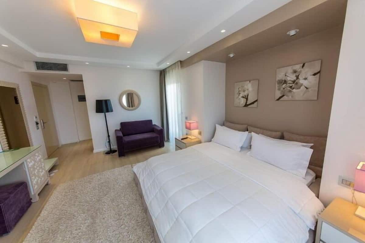 Una habitación de hotel moderna con una cama grande, un sofá, un escritorio y un espejo.