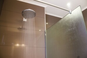 A shower with a glass enclosure and a visible water flow. - Demi Hotel (Sarandë)