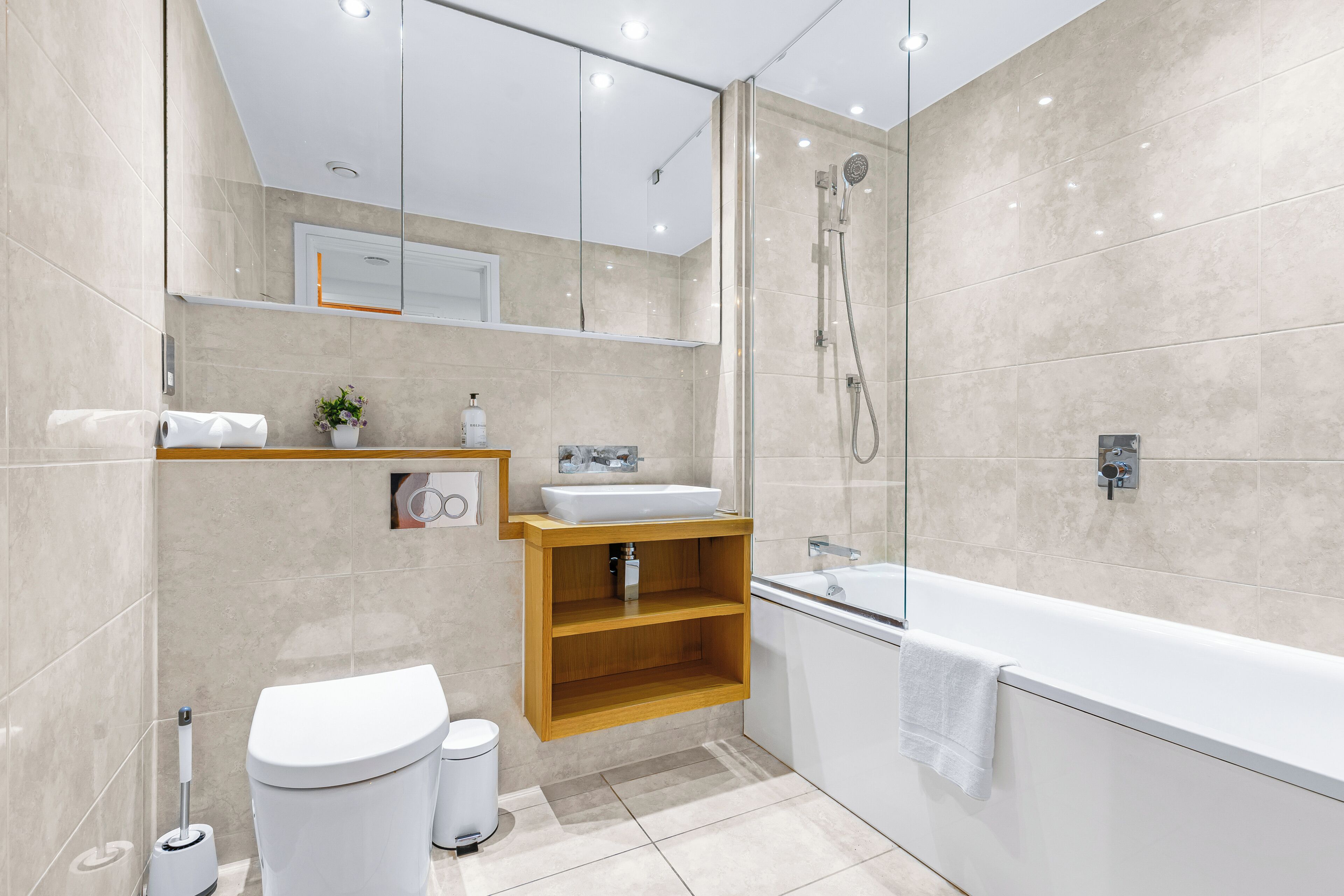 A modern bathroom with a toilet, sink, shower, and bathtub.