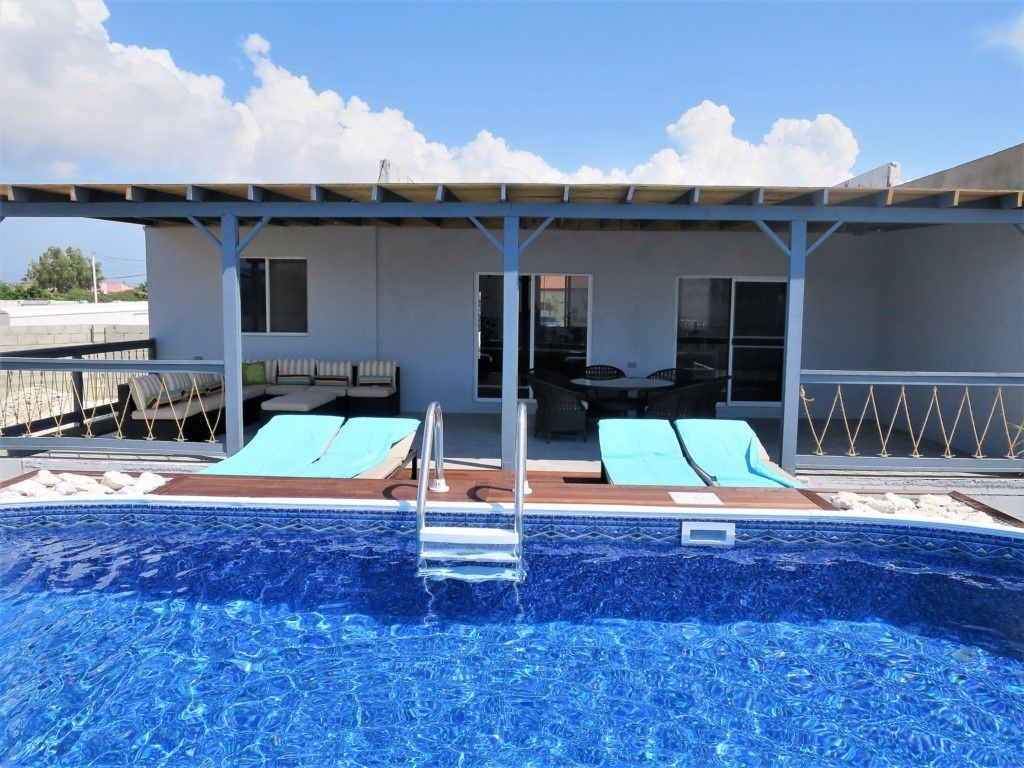 Una piscina al aire libre, sillones reclinables de piscina