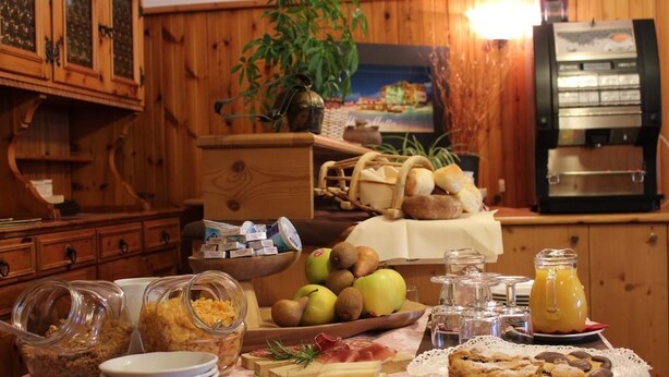 A breakfast buffet with various food items, including fruits, cheeses, and pastries, in a wooden cabin setting. - Bucaneve (Campodolcino)