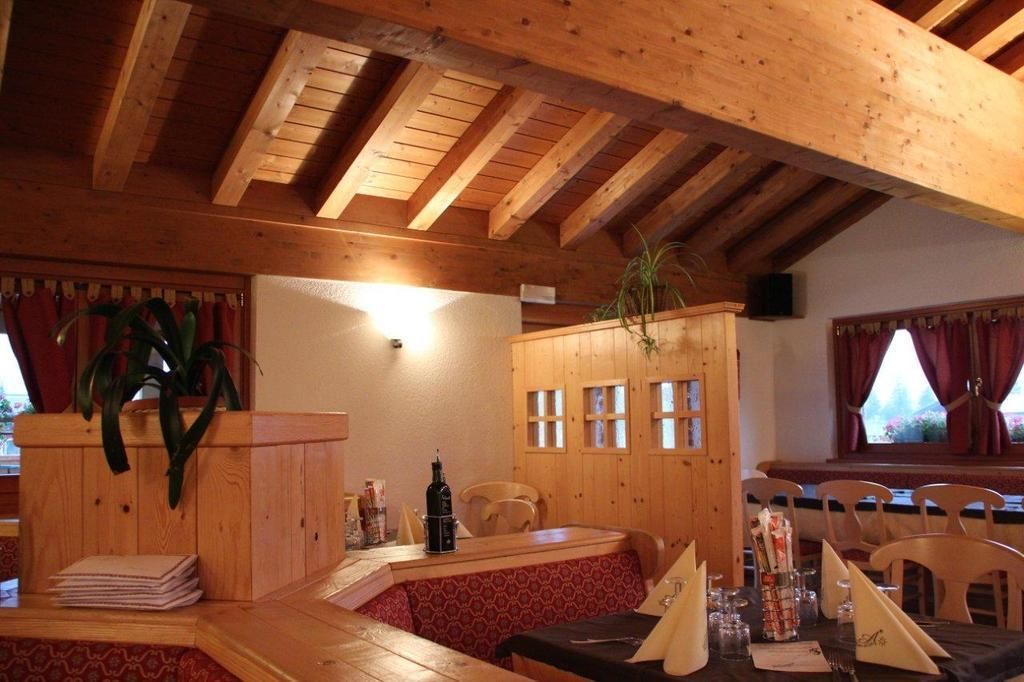 A wooden interior with a high ceiling, a table set for dining, and a plant on the wall.