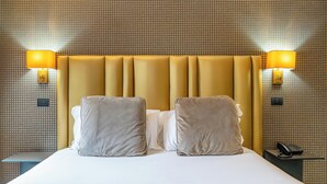 A hotel room with a large bed, two bedside lamps, and a phone on a nightstand. - Via Veneto Suites (Rome)