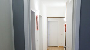 A narrow hallway with wooden flooring, white walls, and doors leading to other rooms. - Hotel Samoggia (Valsamoggia)