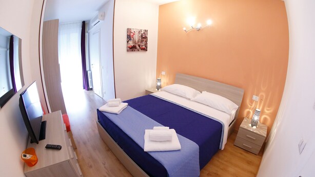 A bedroom with a bed, bedside tables, a desk, and a chair. - Hotel Samoggia (Valsamoggia)