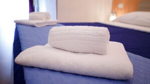 A neatly made bed with a blue bedspread and two white towels stacked on top. - Hotel Samoggia (Valsamoggia)