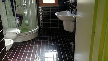 A bathroom with a glass-enclosed shower, a toilet, and a sink.