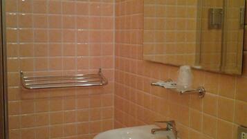Un bagno con lavandino, specchio e uno sgabello.