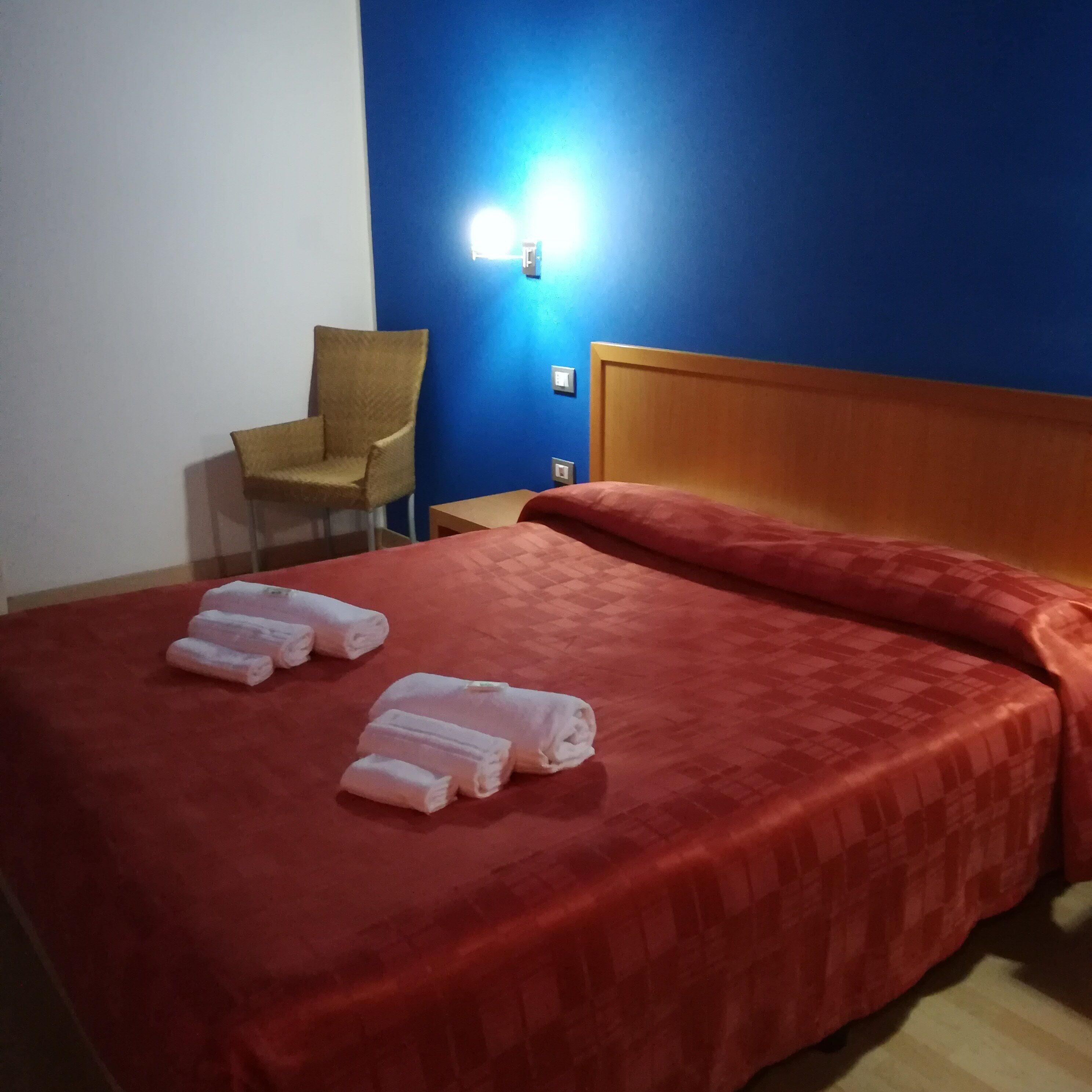 A hotel room with a bed, a chair, and a nightstand.