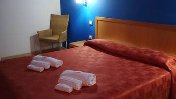 A hotel room with a bed, a chair, and a nightstand.