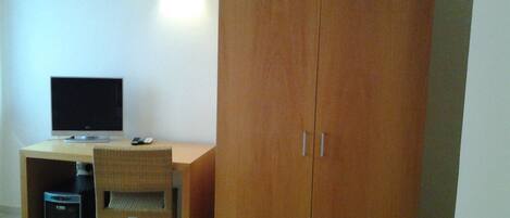 Une pièce comprenant une armoire en bois, un bureau avec un écran d’ordinateur et une chaise.