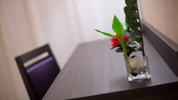 Una pequeña planta en maceta con flores rojas sobre una mesa de madera.