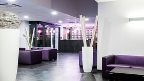 A modern hotel lobby with purple seating, a reception desk, and a visible hotel name sign. - Hôtel Eurocentre Toulouse Nord 3 Stars (Castelnau-d'Estretefonds)