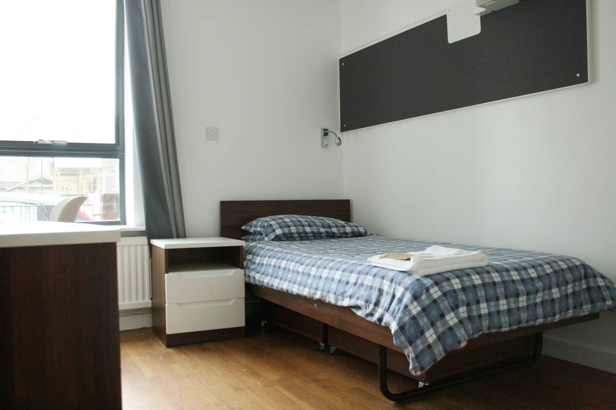 Une chambre à coucher avec un lit, un bureau et une fenêtre.