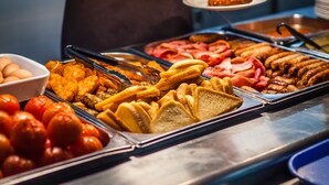Un bufé con una variedad de alimentos, incluyendo carnes, pan y frutas.