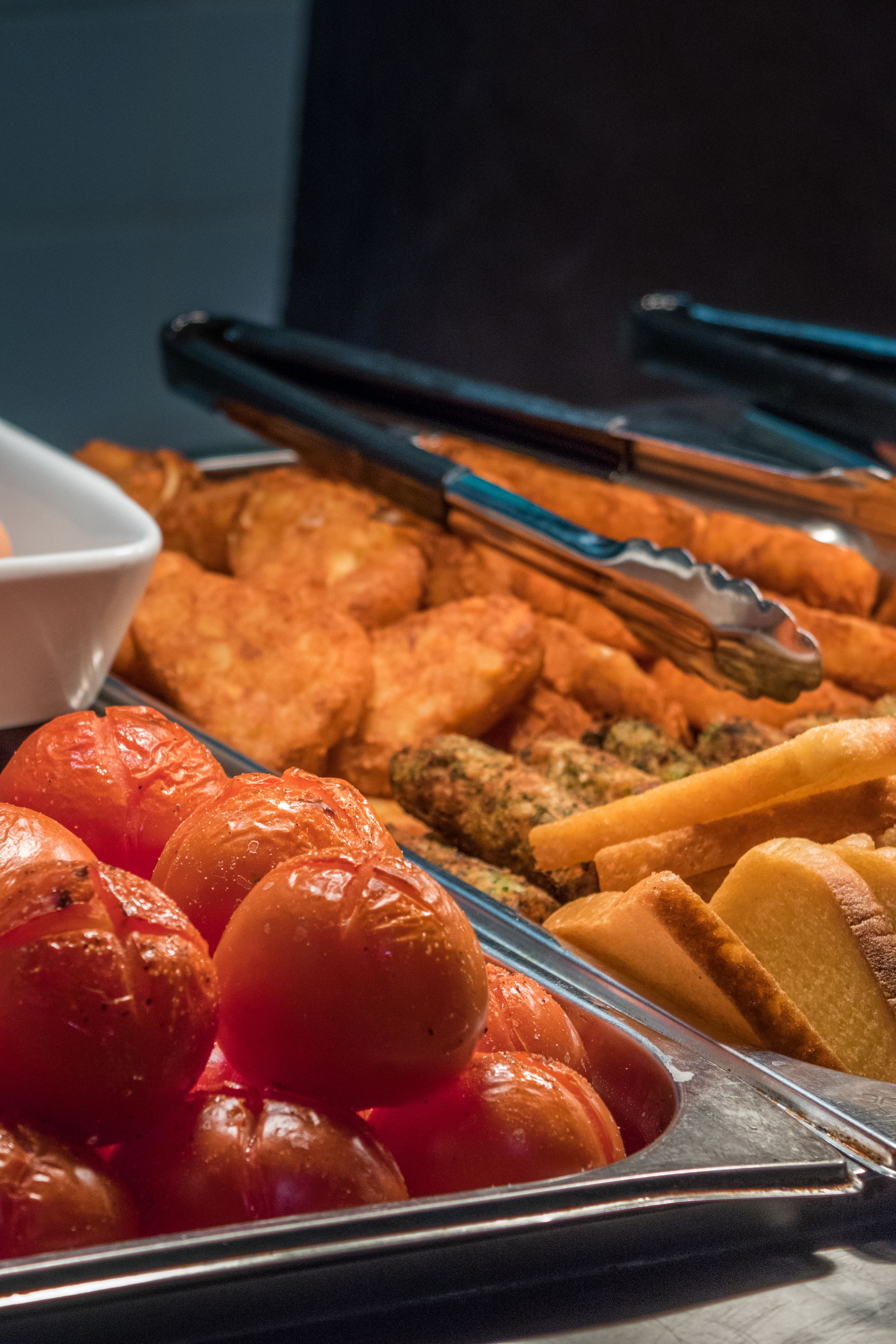 A buffet with various food items including roasted tomatoes, bread, and other dishes.