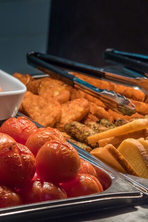 A buffet with various food items including roasted tomatoes, bread, and other dishes. - LSE Rosebery Hall - Campus Accommodation (London)