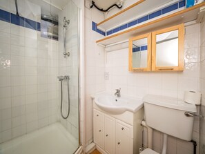 A bathroom with a glass-enclosed shower, a sink with a mirror above it, and a toilet. - LSE Rosebery Hall - Campus Accommodation (London)