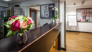 Un mostrador de recepción con un florero, un tablón de anuncios y una pizarra.