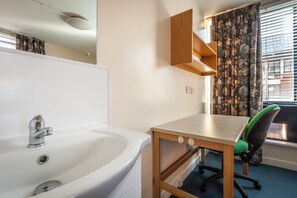 A bathroom with a sink, mirror, and wooden cabinet. - LSE Rosebery Hall - Campus Accommodation (London)
