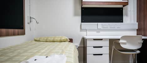A bedroom with a bed, a desk, a chair, and a window.