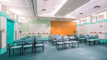 A conference room with rows of chairs, a whiteboard, and a wooden panel wall.