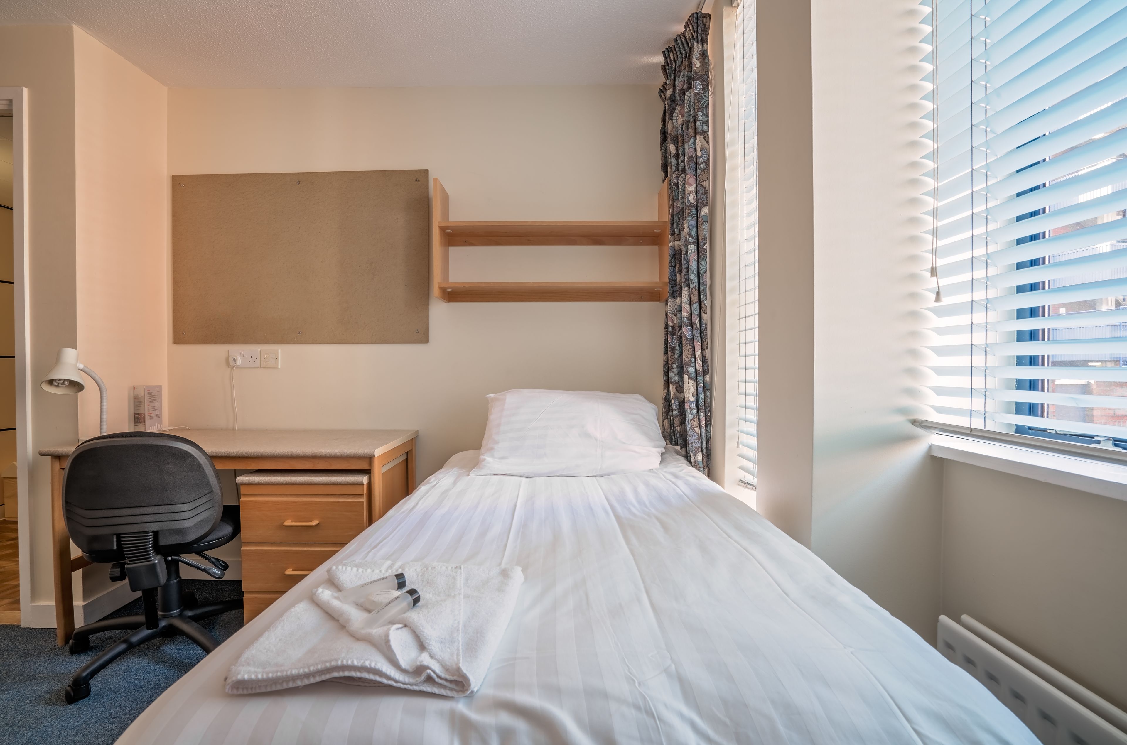 Un dormitorio con cama, escritorio y silla.
