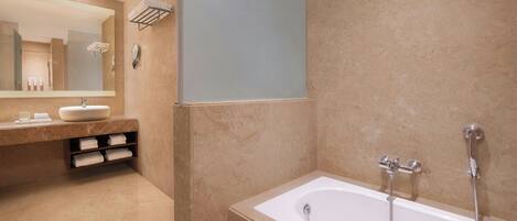 Un baño moderno con un espejo grande, un lavamanos, una bañera y un perchero para toallas.