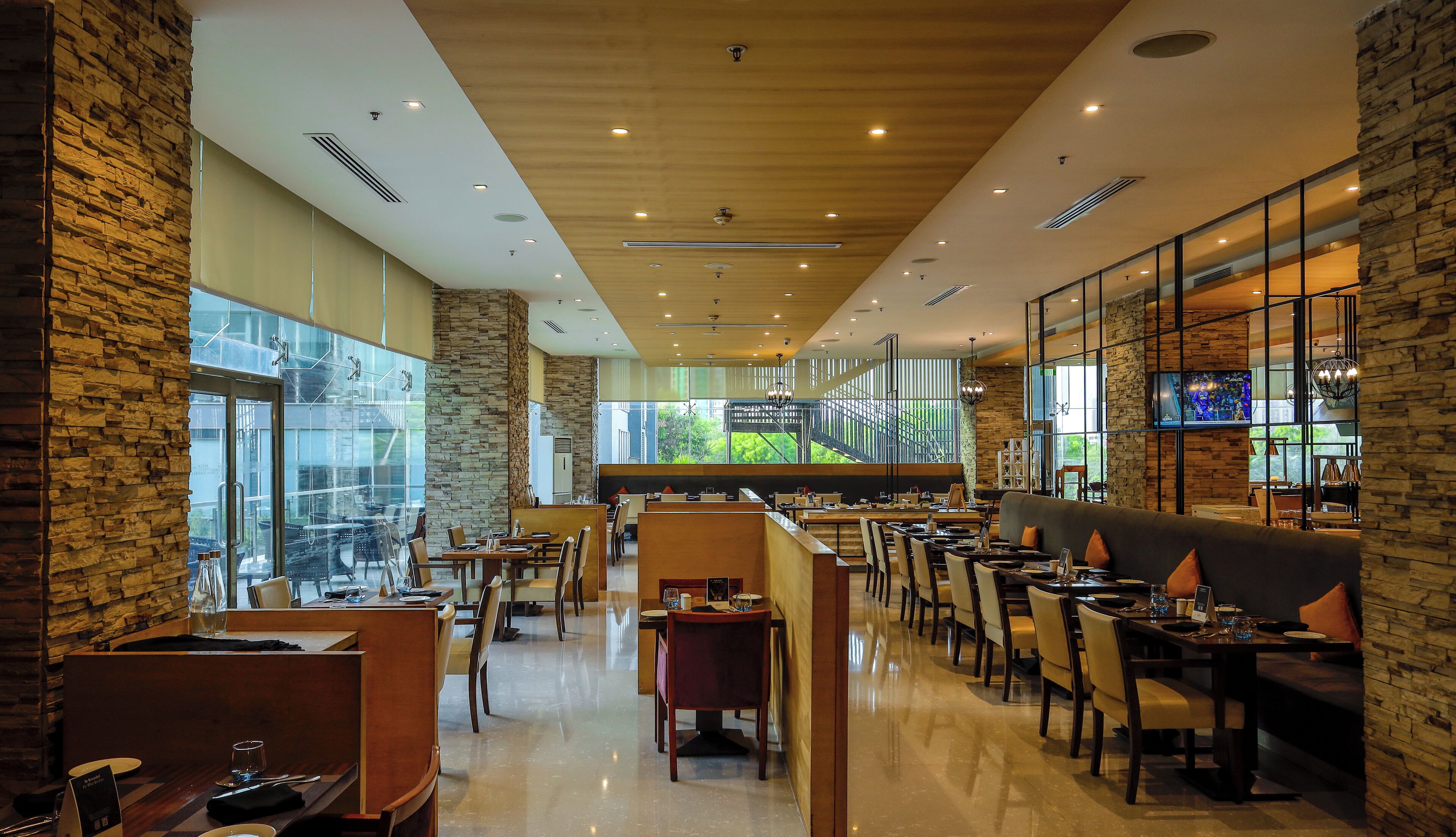 Un restaurante espacioso con techos altos, paredes de piedra y ventanas amplias que ofrecen vistas al exterior.