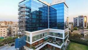 Un edificio moderno de varios pisos con amplias fachadas de vidrio y una escalera prominente a la izquierda.