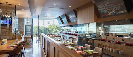A modern restaurant with a long counter, wooden flooring, and a chef preparing food at the counter.